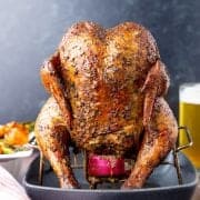 Chicken on beer can with beer in backround.