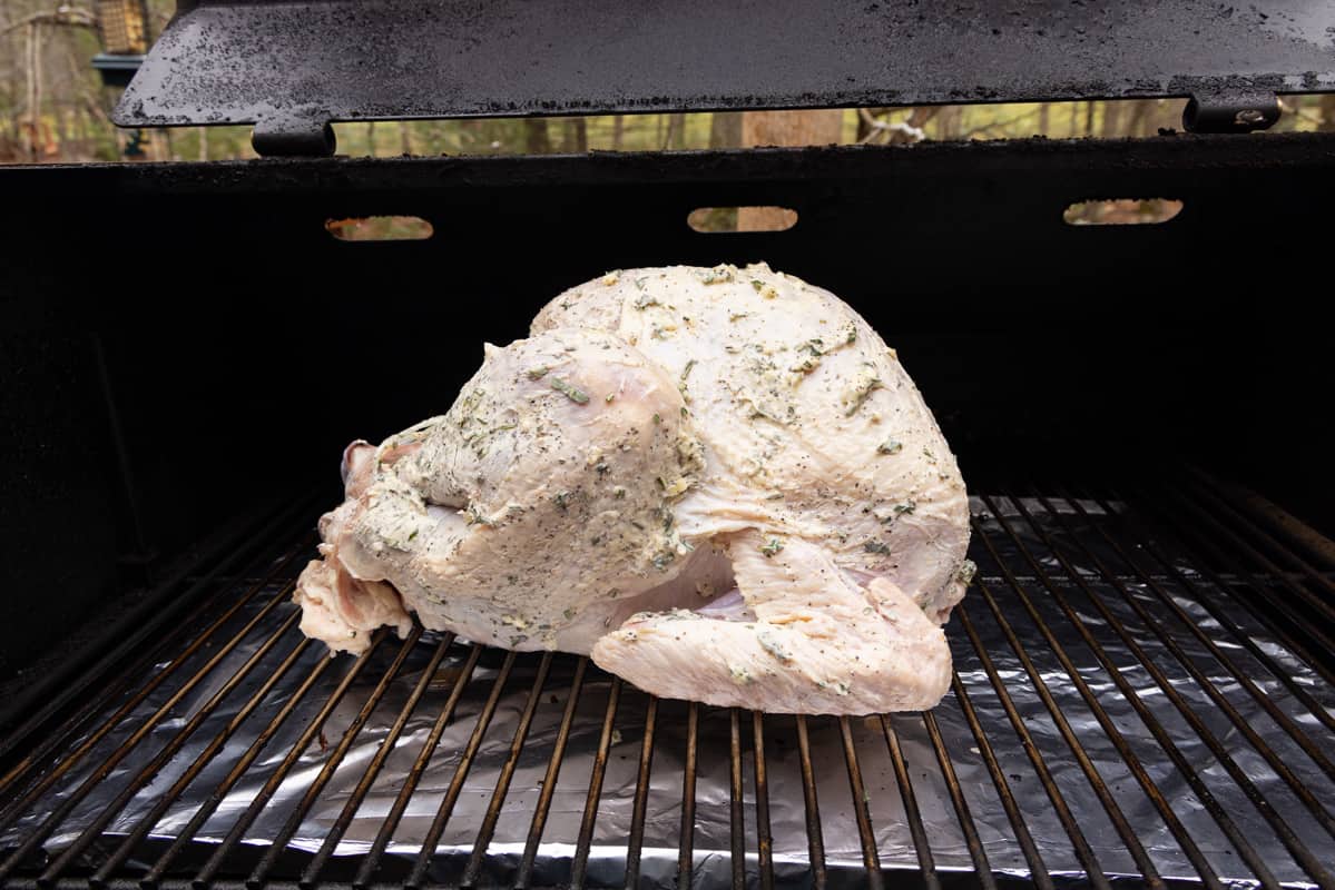Seasoned raw turkey on smoker grate ready to be cooked.