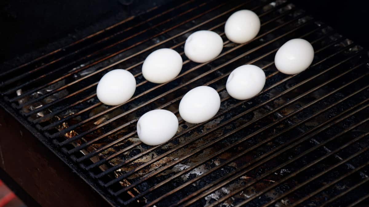 Eight peeled eggs on a grill.