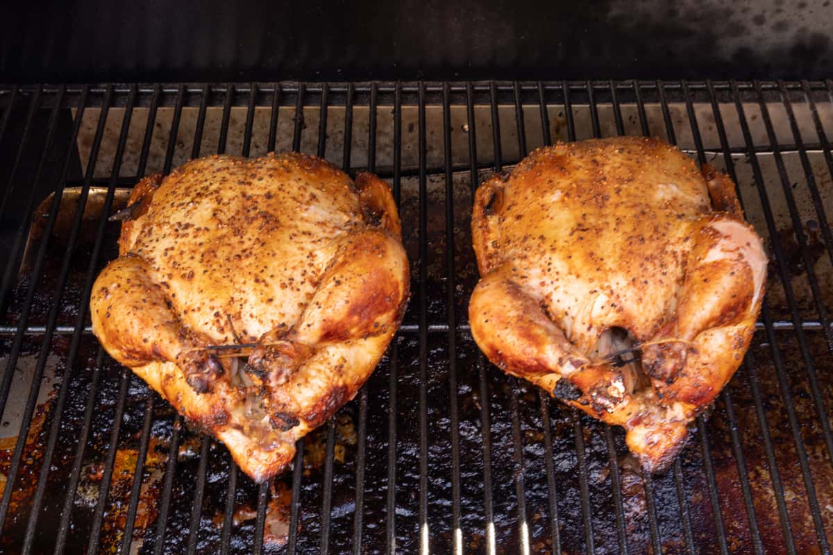 Two whole chickens cooking on grill.