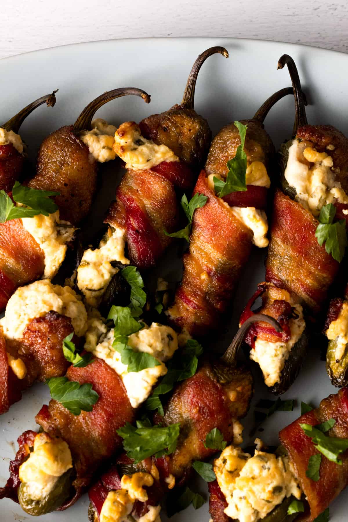 Bacon wrapped jalapeno poppers on white plate.