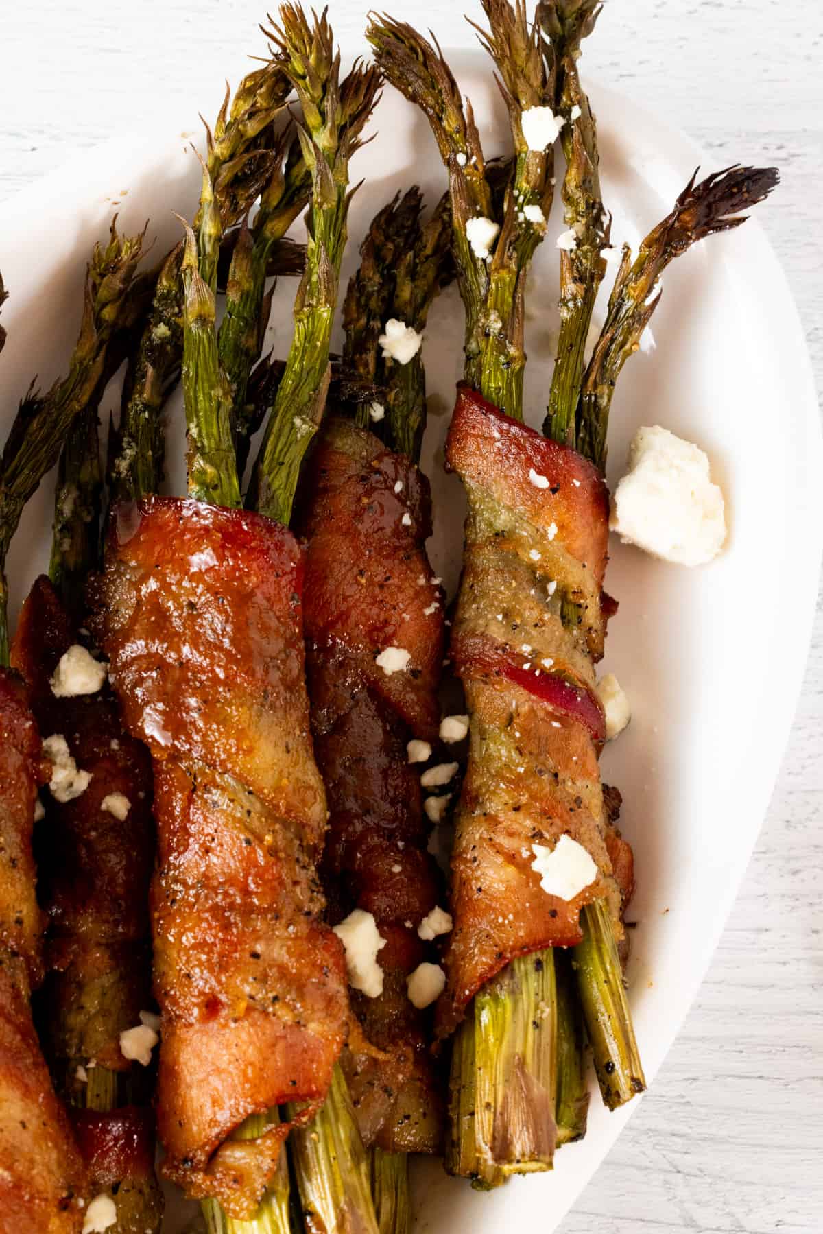 Asparagus wrapped in bacon on white plate.