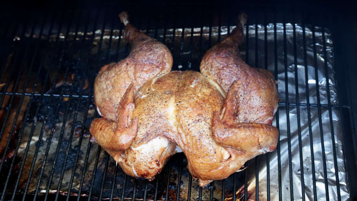 Turkey being cooked on smoker laying directly on grill grates.