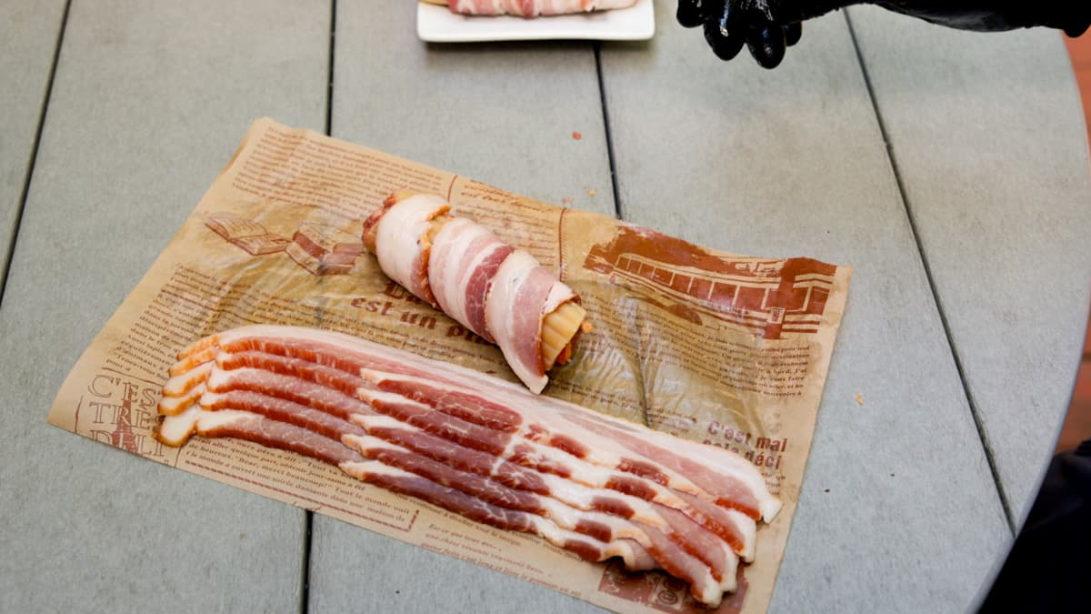 Bacon on table with a pasta shell wrapped with a piece of bacon.