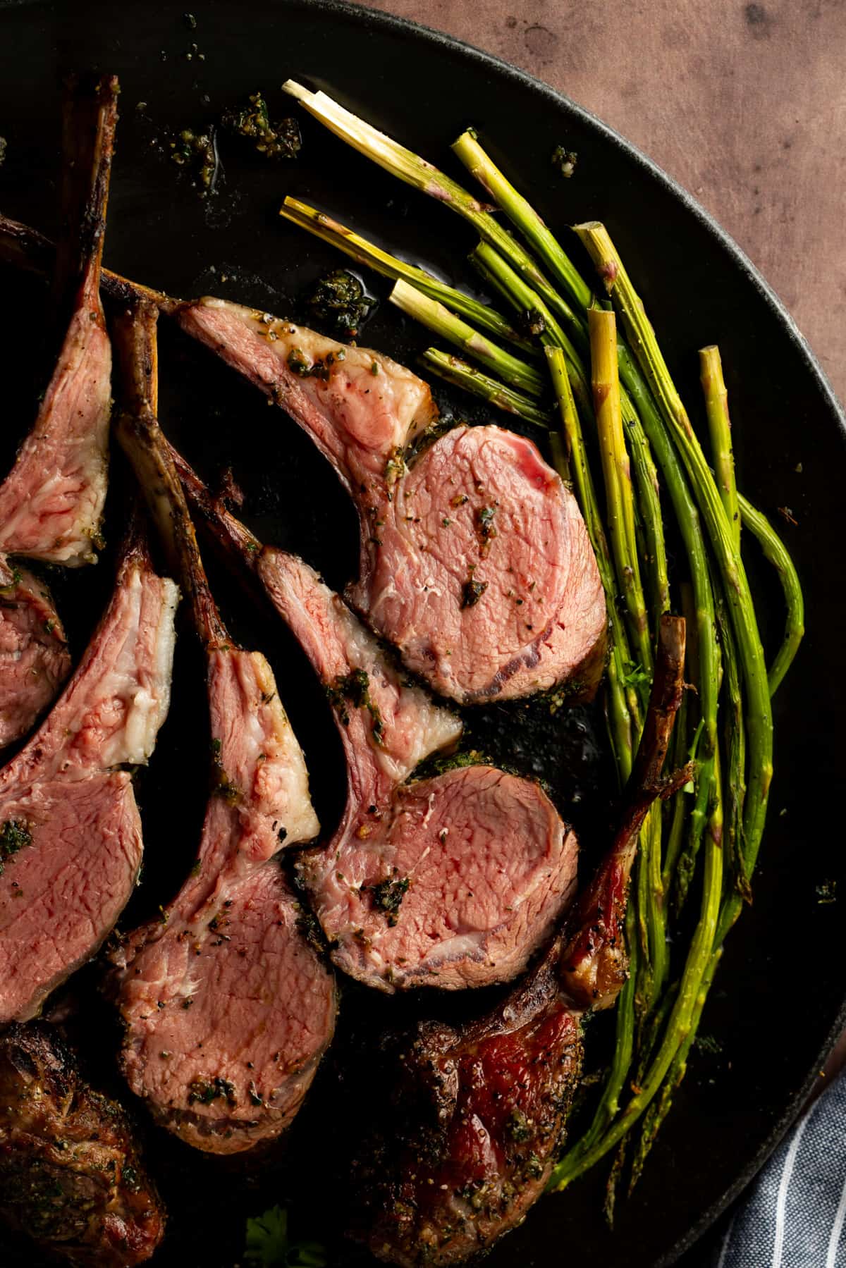 Lamb chops on black plate with a side of asparagus.