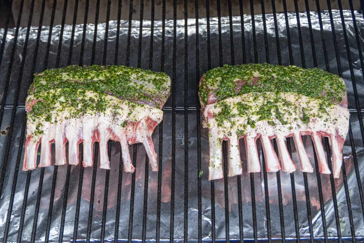Two racks of lamb on smoker covered in marinade.