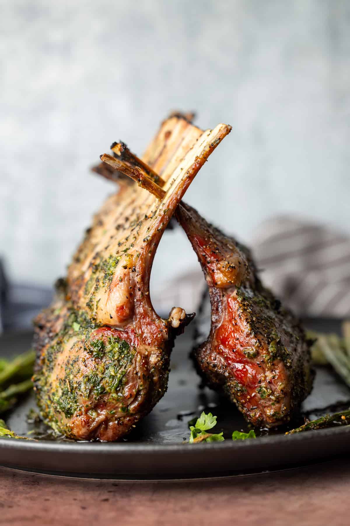 Two racks of lamb cooked on top of a black plate with white background.